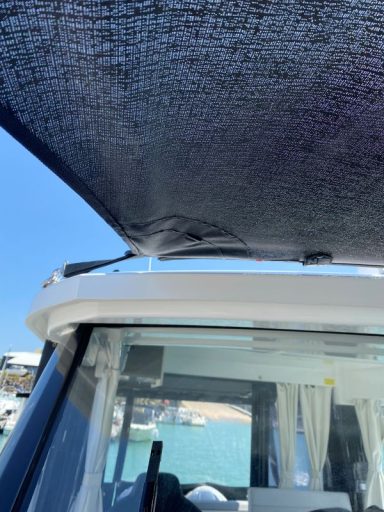 Sicht auf das Dach eines Boots mit Sonnenschutz und Blick auf den Wasserhorizont.